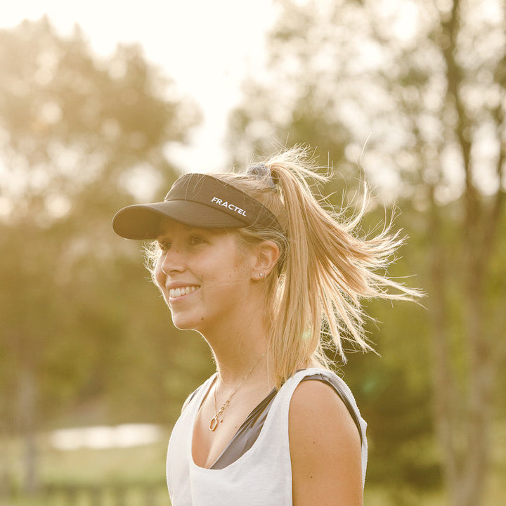 Woman wearing a cap with 'Fractel' branding outdoors