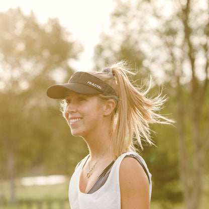 Woman wearing a cap with 'Fractel' branding outdoors