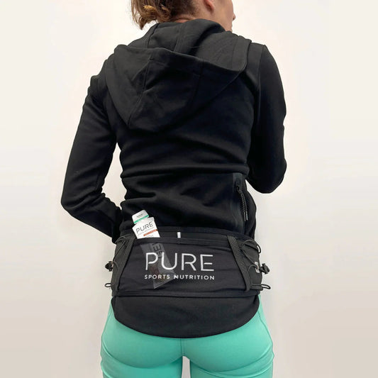 Person wearing a black hoodie and green leggings with a black waist bag featuring 'PURE Sports Nutrition' on a white background.